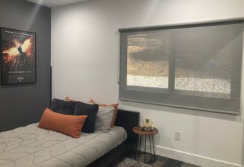 Modern Yorba Linda bedroom with roller shades fully lowered, showing privacy and style with pull down window shades.